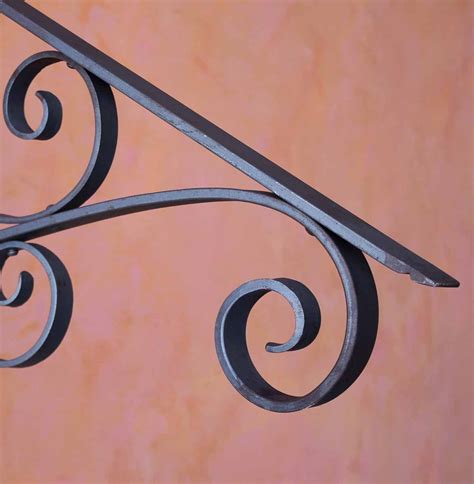the corner of a wrought iron railing against an orange wall with swirls on it