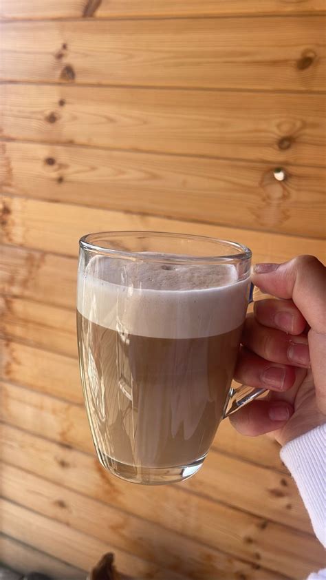 a person holding a cup of coffee in front of a wooden wall