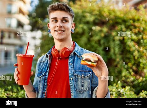 Young caucasian guy eating burger and soda at the city Stock Photo - Alamy