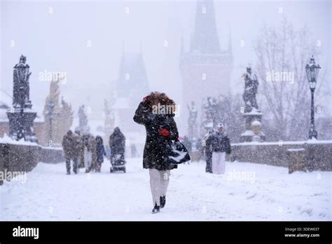 A woman crosses the medieval Charles Bridge during a heavy snowfall in