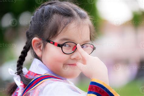 colegiala con uniforme de niña. la niña usa el dedo índice para empujar