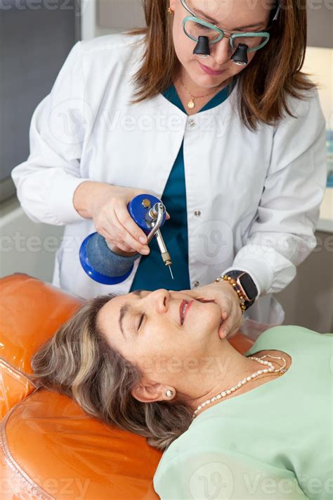 Dermatologist applying cryotherapy for skin lesions on a senior female