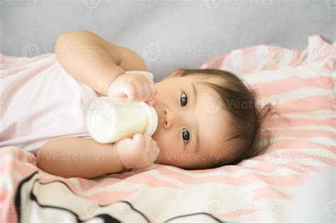 A baby girl is drinking milk bottle, family, child, childhood and
