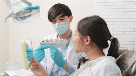 Asian male dentist explains orthodontic care and whitening to a young