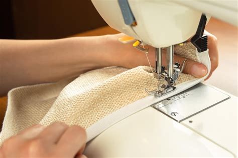female hands stitching white fabric  modern sewing machine close
