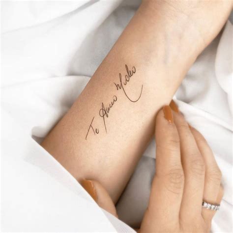 "Te amo mucho" lettering tattoo on the inner forearm.
