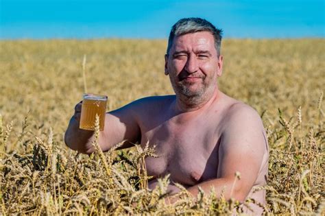 Premium Photo | A fat man with a beer belly drinks beer in a wheat field