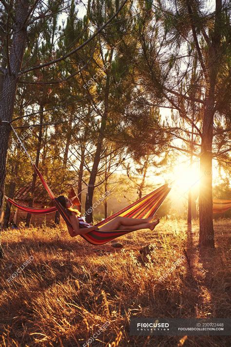 Woman lying in hammock at sunny woods — nature, meadow - Stock Photo