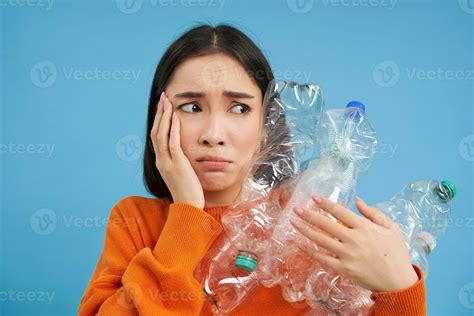 Sad asian woman holding plastic bottles, looking troubled and upset