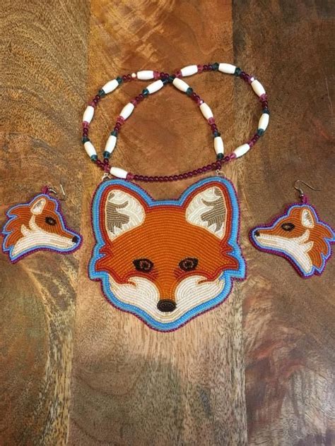 a necklace and earring set with an orange fox head on the beaded cord