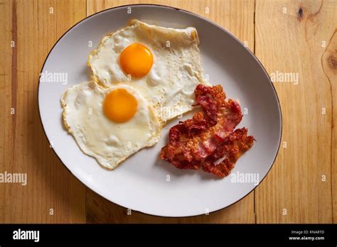 Breakfast bacon and eggs over easy on wood table Stock Photo - Alamy