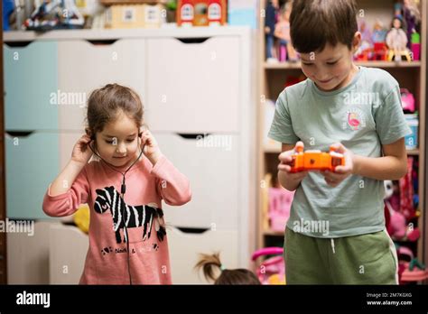 Brother hold remote control and sister listening to music through wired ...