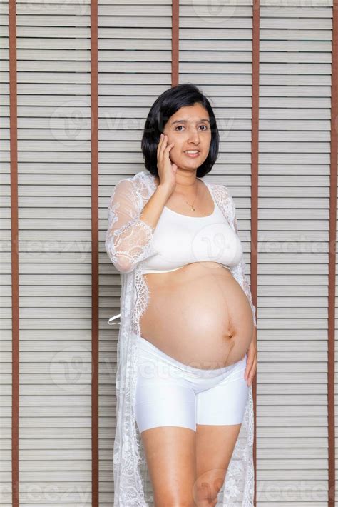 Portrait of a pregnant woman touching her big belly close up, mother