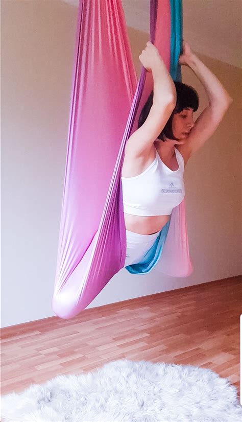 a woman is doing aerial yoga on a hammock