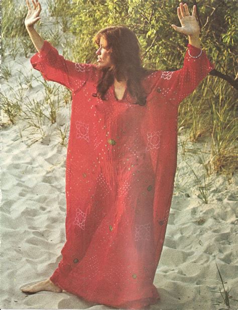 Carly Simon wearing red caftan standing on the sand. Photo from CIRCUS
