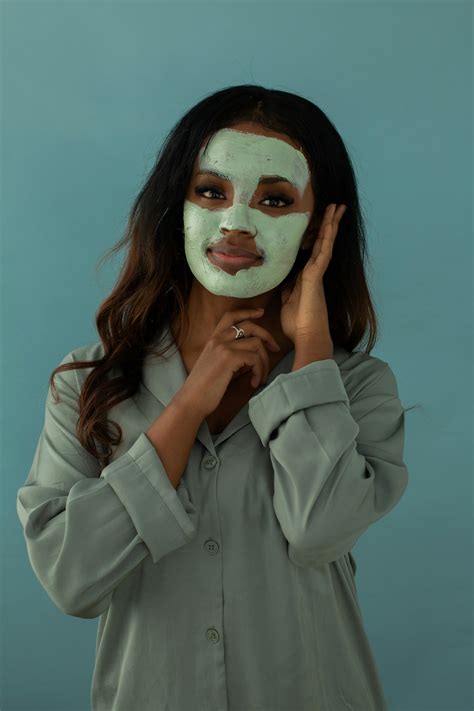 Woman with Black Facial Mask on Her Face Holding a Glass of Water