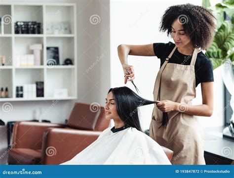 young black hairdresser cutting hair  female customer  salon stock