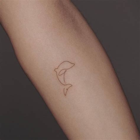Single line dolphin tattoo on the inner forearm