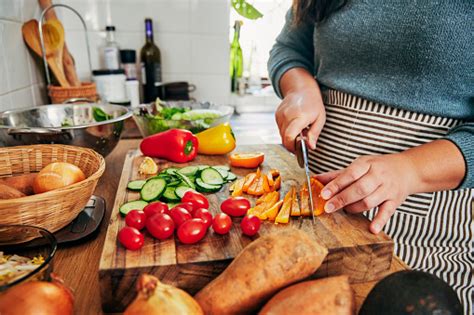 Shot Of A Woman Cutting Vegetables To Be Cooked Stock Photo - Download