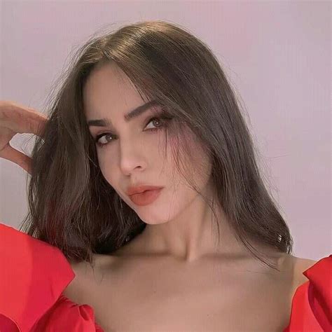 a close up of a person wearing a red dress and holding her hair in the air