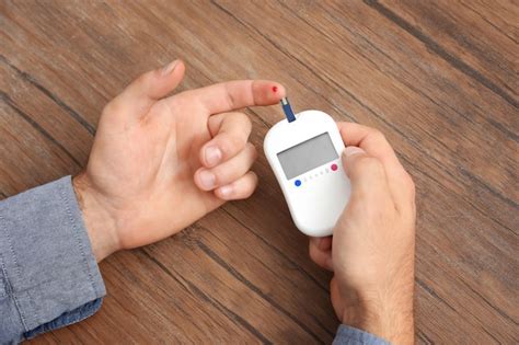 Premium Photo | Hands of man using digital glucometer on wooden ...