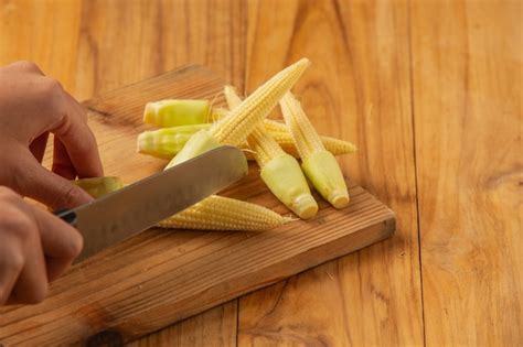 photo young woman hand chopping corn   chopping block