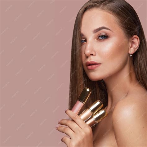 Hermosa joven con maquillaje nude natural con cosmética en las manos
