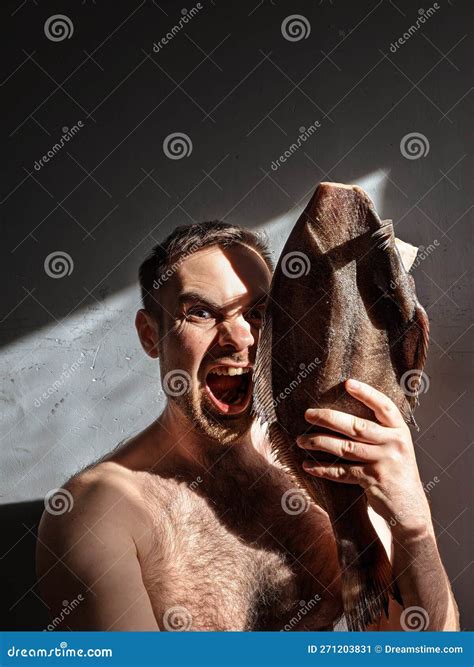 A Joyful Man with His Mouth Open Holds a Large Halibut in His Hand