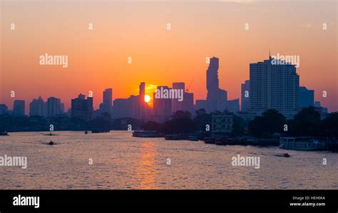 Sunrise over the scenic skyline at Bangkok, Thailand, viewed in backlight at sunrise with orange ...