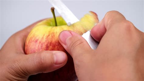 Hand peeling apple with knife close up. Woman peeling a red apple in