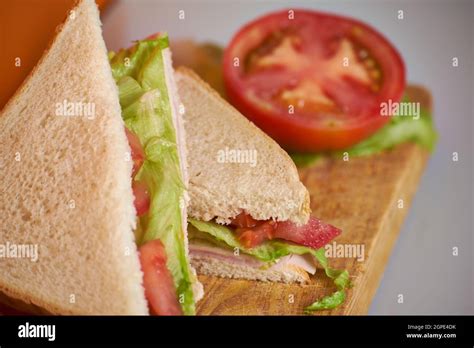 ham  cheese sandwich  tomato  lettuce  wood board table