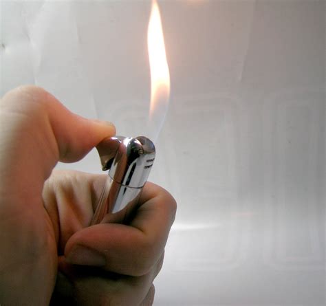 hand holding  silver lighter producing flame  stock photo freeimages