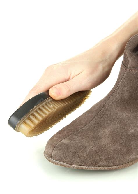 Premium Photo | Hand with brush cleaning suede shoes isolated on white