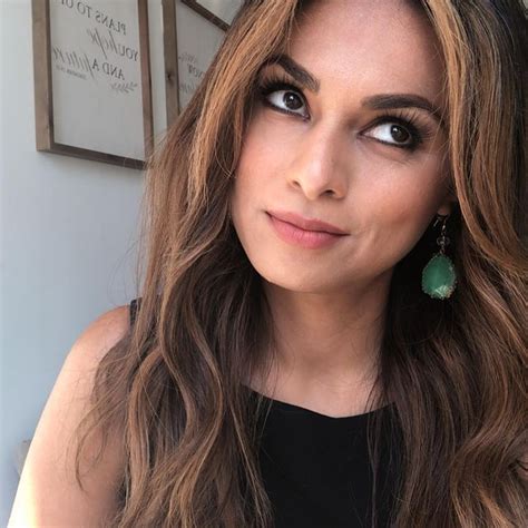 a close up of a person with long hair and wearing green earring's
