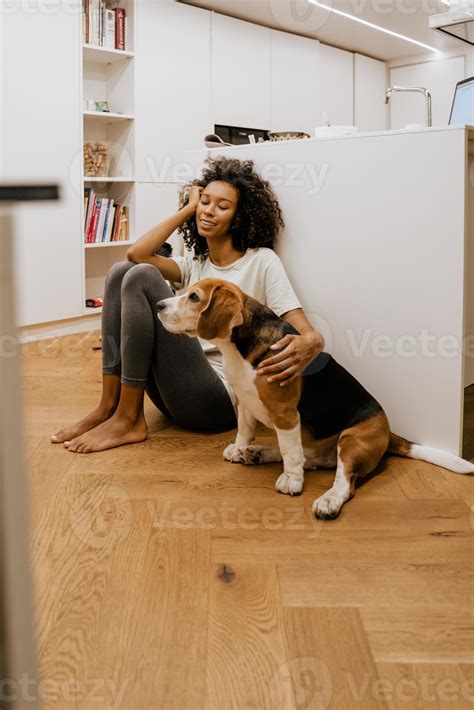Black young woman strokes her dog while sitting on floor 3530631 Stock