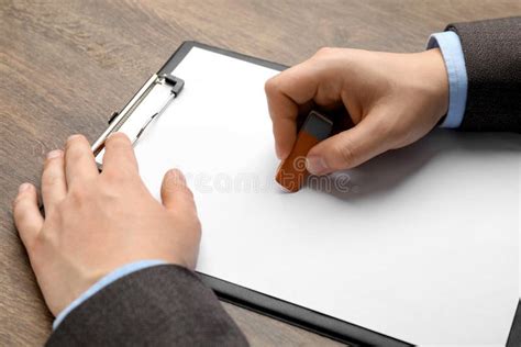 man erasing   paper  wooden table closeup stock photo