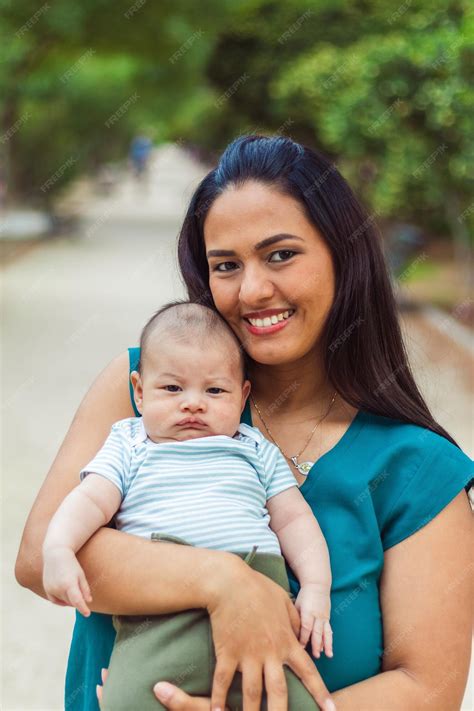 Premium Photo | Young latin mom smiling with her baby in a park looking