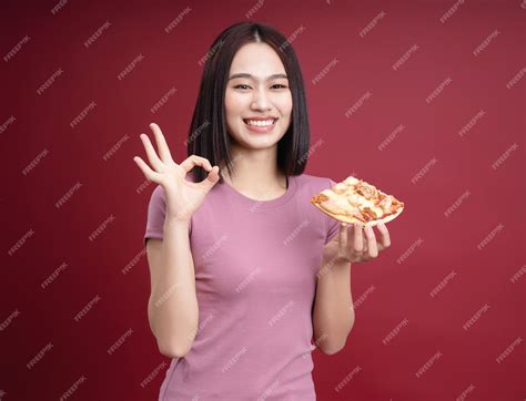 Premium Photo | Young asian woman eating pizza on background