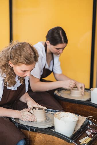 dua wanita membuat tembikar  atas roda tembikar membentuk tanah liat