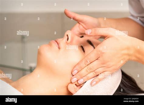 Young caucasian woman with closed eyes getting a facial massage in a beauty clinic Stock Photo