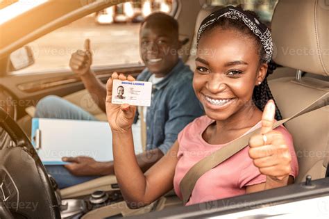 Happy african girl with driving license and her instructor showing