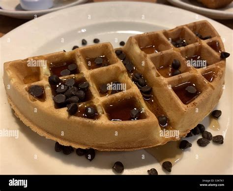 Half waffles with chocolate chips and syrup on a white round plate ...
