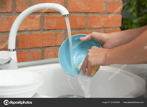 woman washing dishes kitchen sink closeup view cleaning chores stock