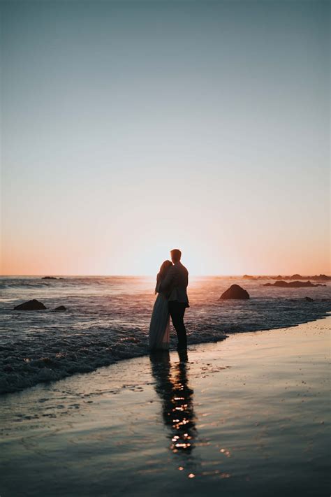 Download Couple Sunset On Beach Embracing Picture | Wallpapers.com