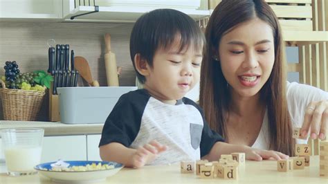 Asian mother and son play wooden jigsaw puzzle together happily. Love