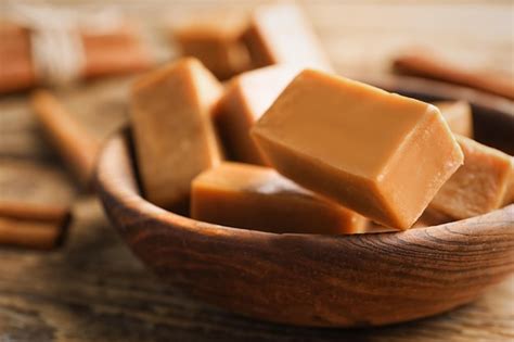 Premium Photo | Plate with sweet caramel candies on wooden table