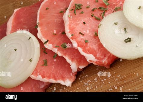 Juicy raw pork loin chops with onion slices and spices on wooden ...