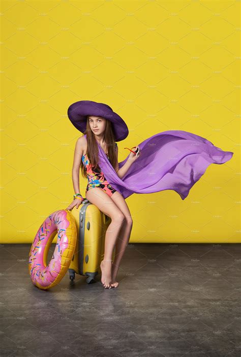 Stunning girl model in a colorful bikini, hat, pareo with a suitcase