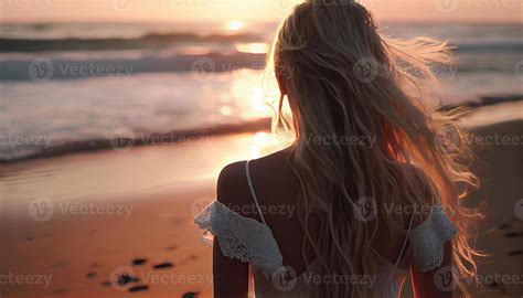 Beautiful blonde woman with long hair in a dress alone at sunset on the