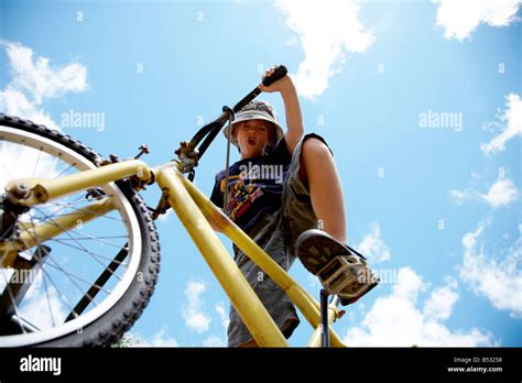 Boy 8 riding mountain bike from low angle with blue sky above mr Stock ...